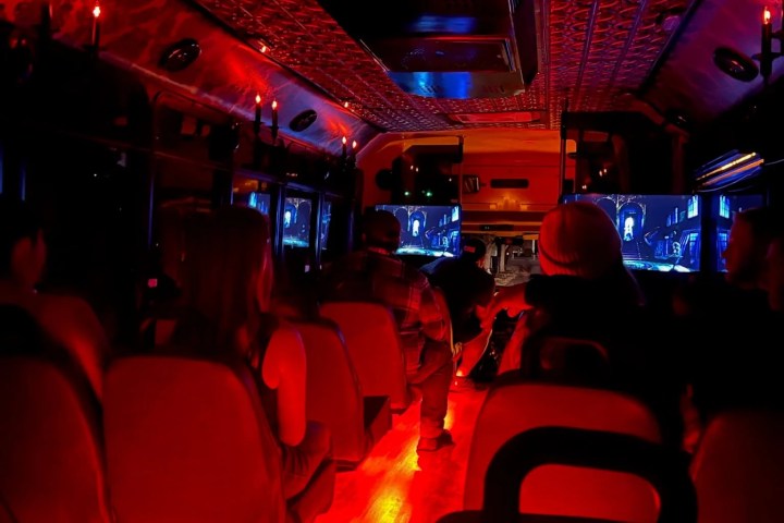 Dimly lit bus interior with red lights and ornate ceiling design.