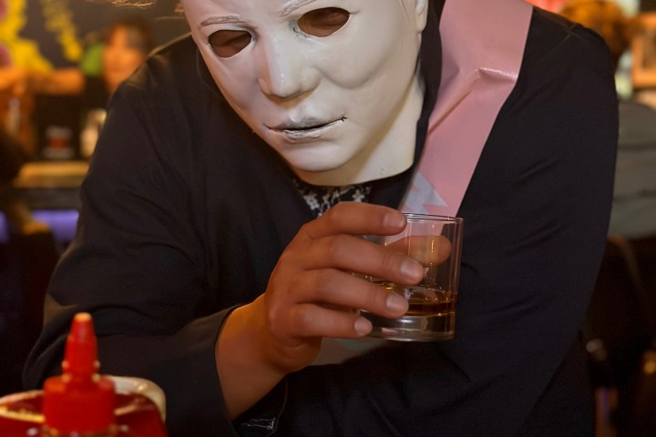 michael myers sitting at a table drinking whiskey