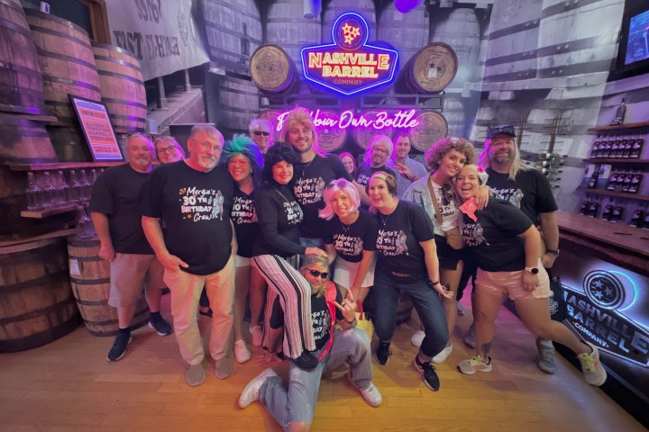 a group of people posing in front of whiskey barrels