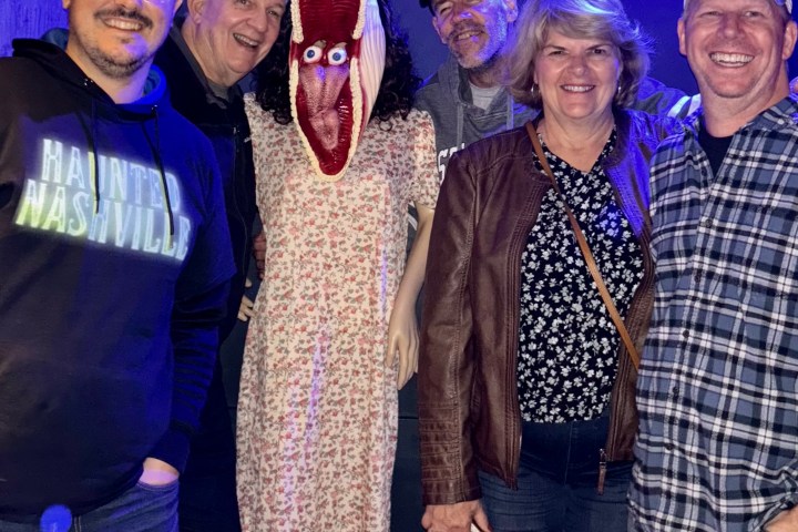 a group of people posing in front of beetlejuice in hidden bar nashville