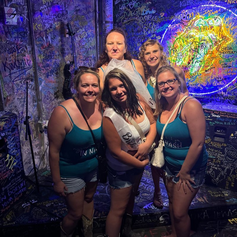 a woman standing in front of a group of people posing for the camera