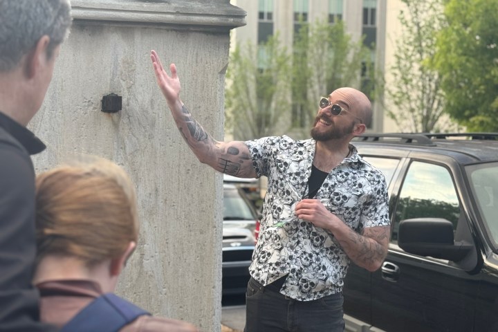 a man standing in front of a building talking on a cell phone