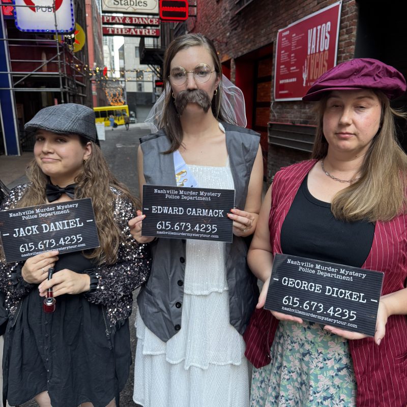 a group of murder mystery tour people posing in printer's alley nashville