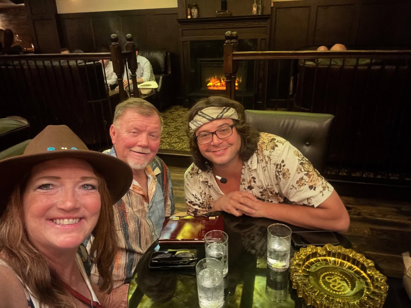 Three people smiling at a restaurant table with drinks.