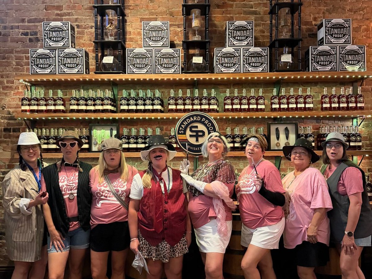 Group of women in casual outfits posing in front of shelves with jars and boxes.