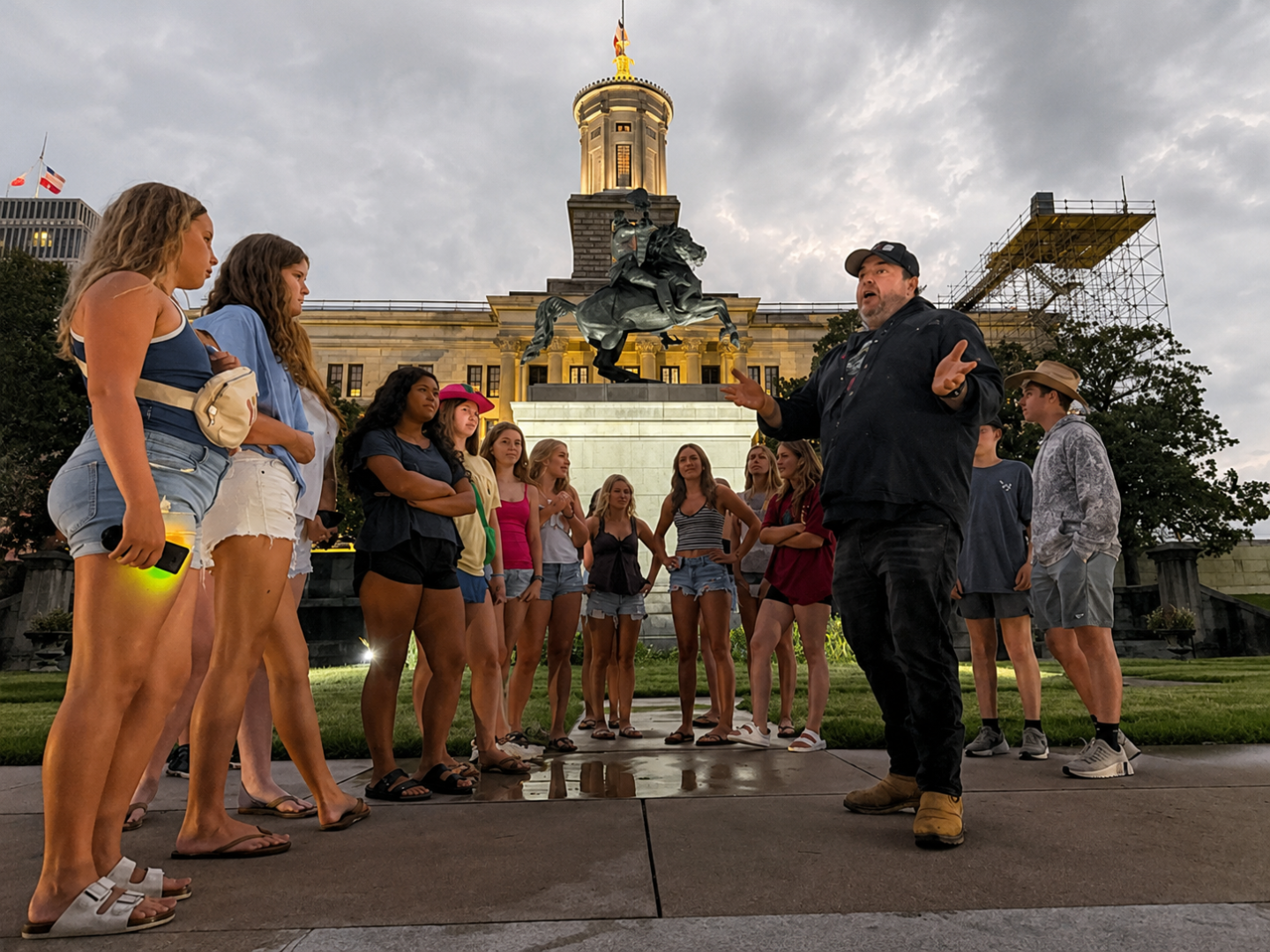 Group of people gathered around a man in front of the Tennessee state capitol in nashville on a haunted ghost bus tour